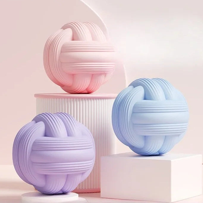 Three spherical decorative items in pastel colors on a light pink background
